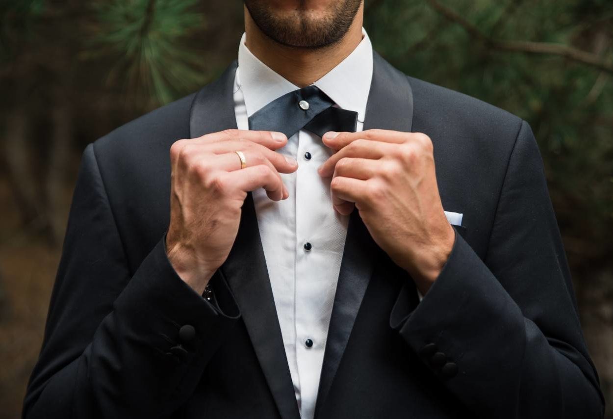 Homem vestindo um blazer ajustando a sua gravata.