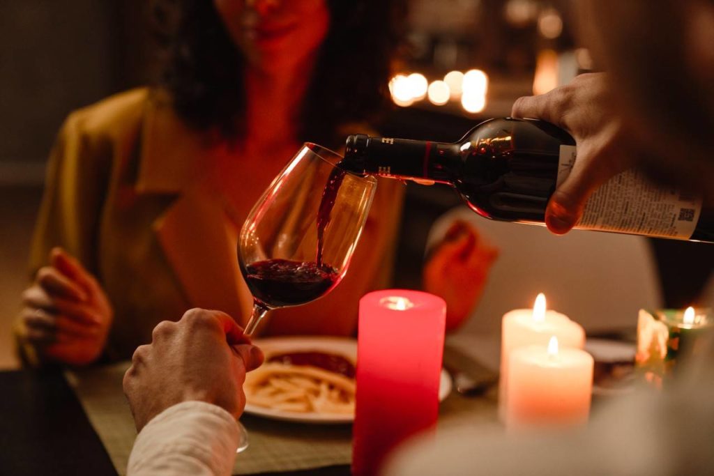 Casal em um jantar romântico com vinho el velas.