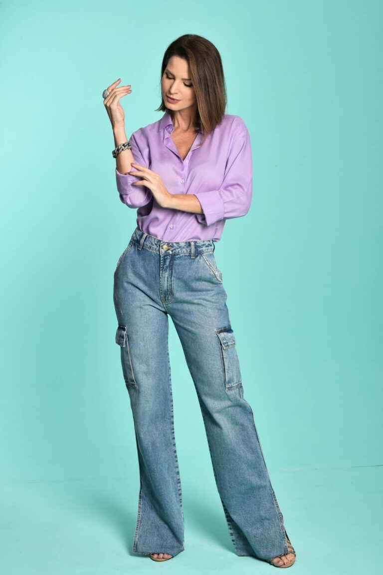 Moça esta vestindo uma camisa lilas com calça jean