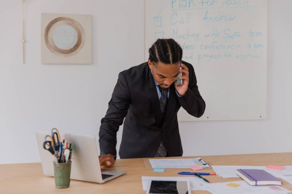 Homem em um escritório realizando anotações em quanto fala no telefone