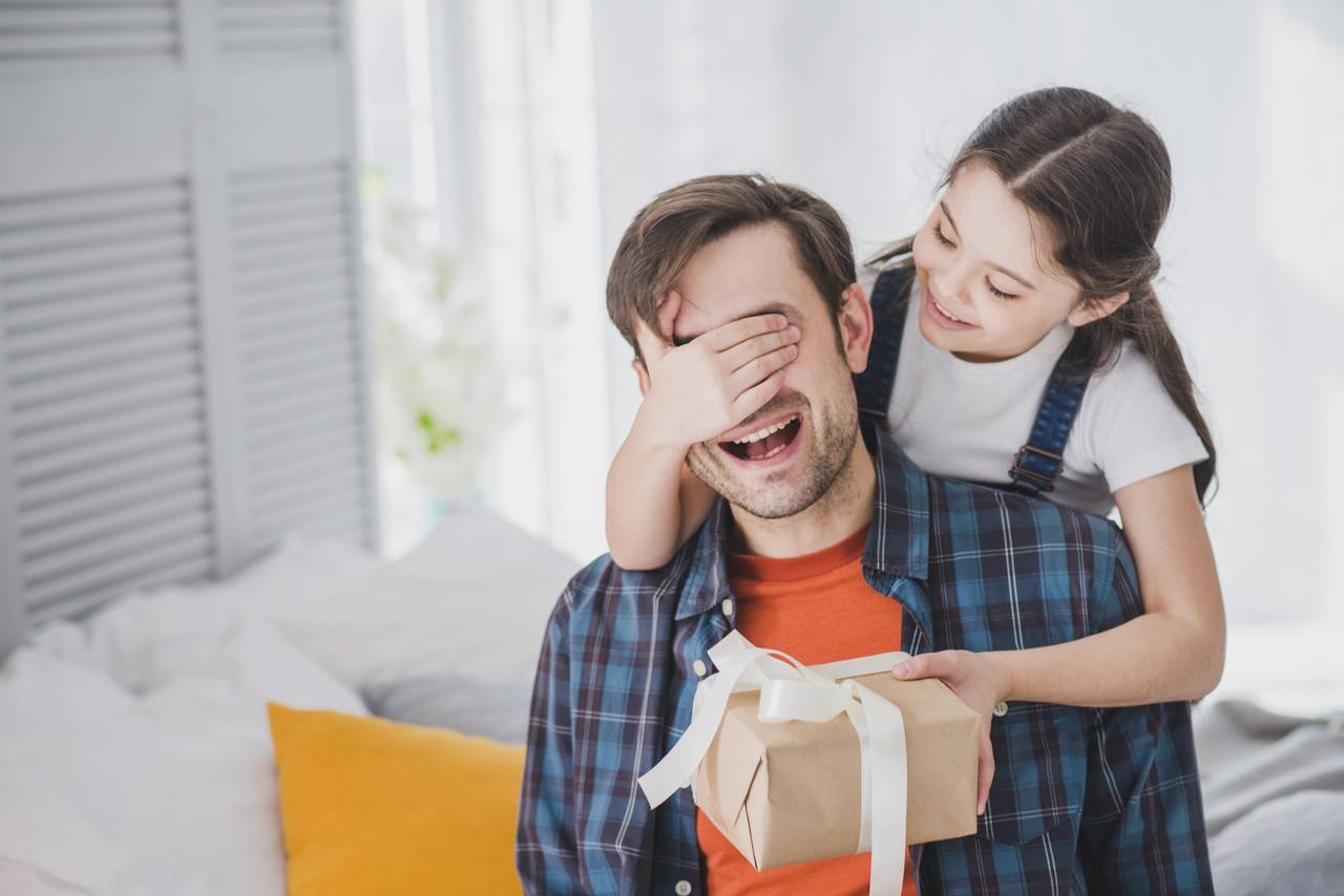 Filha cobrindo os olhos do pai para entregar o presente para ele.