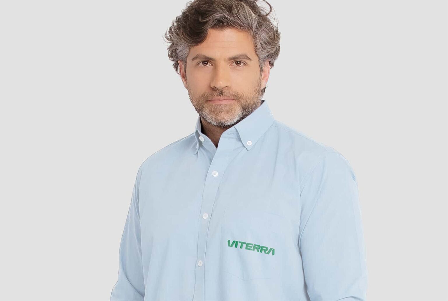 Homem vestindo camisa social masculina azul clara com logotipo Viterra aplicado no lado esquerdo do peito.