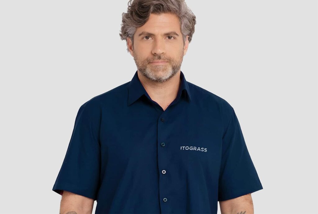 Homem vestindo camisa social masculina de manga curta na cor azul marinho, com logotipo Itograss bordado no lado esquerdo do peito.