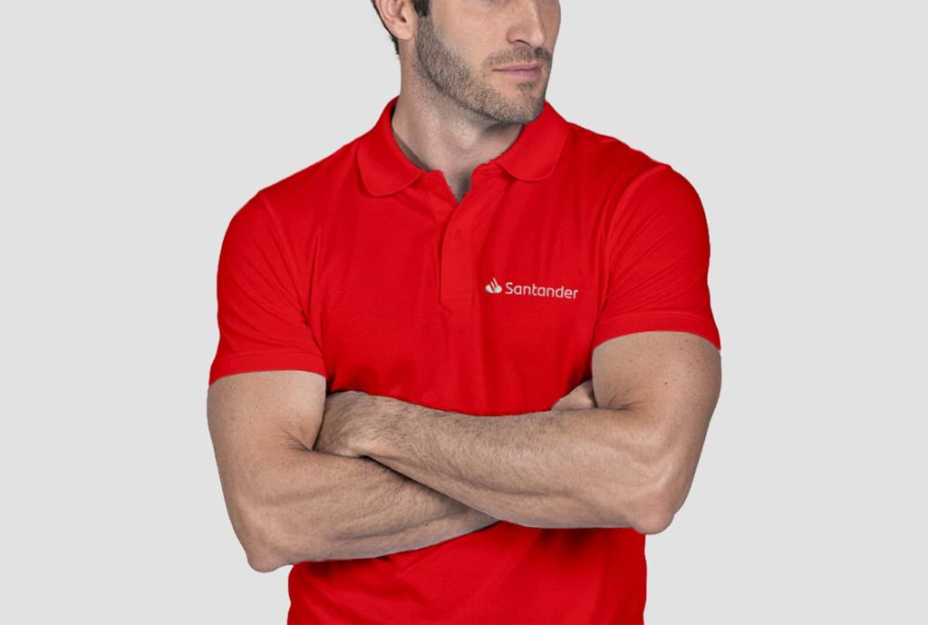 Homem vestindo camisa polo masculina vermelha com logotipo Santander aplicado no lado esquerdo do peito.