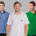 Camisas corporativas masculinas personalizadas, sendo um modelo jeans do Banco da Amazônia, um modelo branco da Credicitrus e uma polo verde da PicPay, todas com logotipo aplicado no peito.