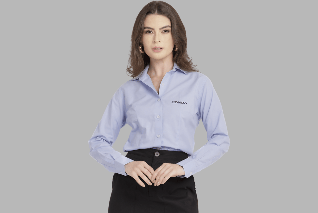 Mulher vestindo camisa social feminina azul clara com logotipo Honda aplicado no lado esquerdo do peito.