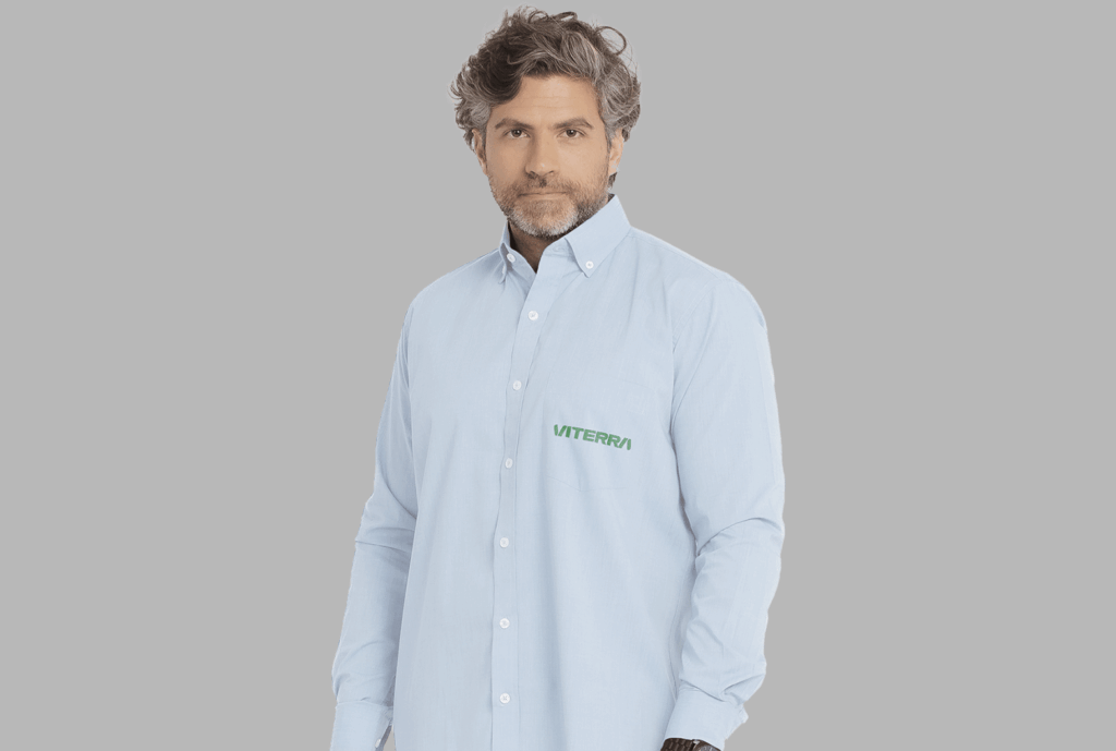 Homem vestindo camisa social masculina azul clara com logotipo Viterra aplicado no lado esquerdo do peito.
